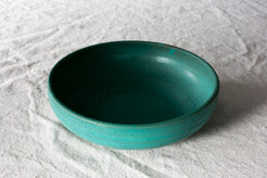 Wander Pasta Bowl in speckled turquoise glaze viewed from a high angle on woven linen.