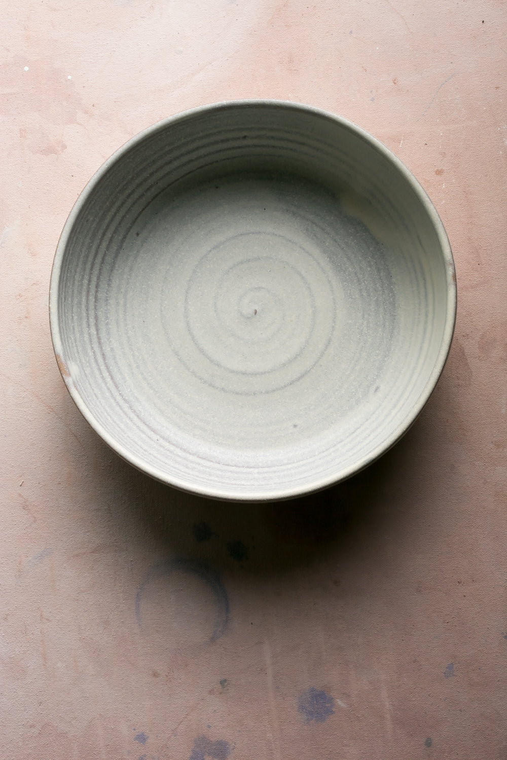 Wander Serving Bowl: top view of an off-white stoneware bowl with throwing rings, set on a studio surface.