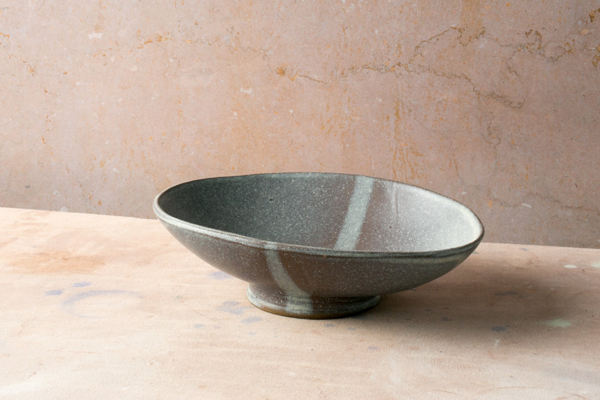 Wander Footed Oval Server in speckled grey glaze with a subtle stripe, resting on its raised pedestal foot.