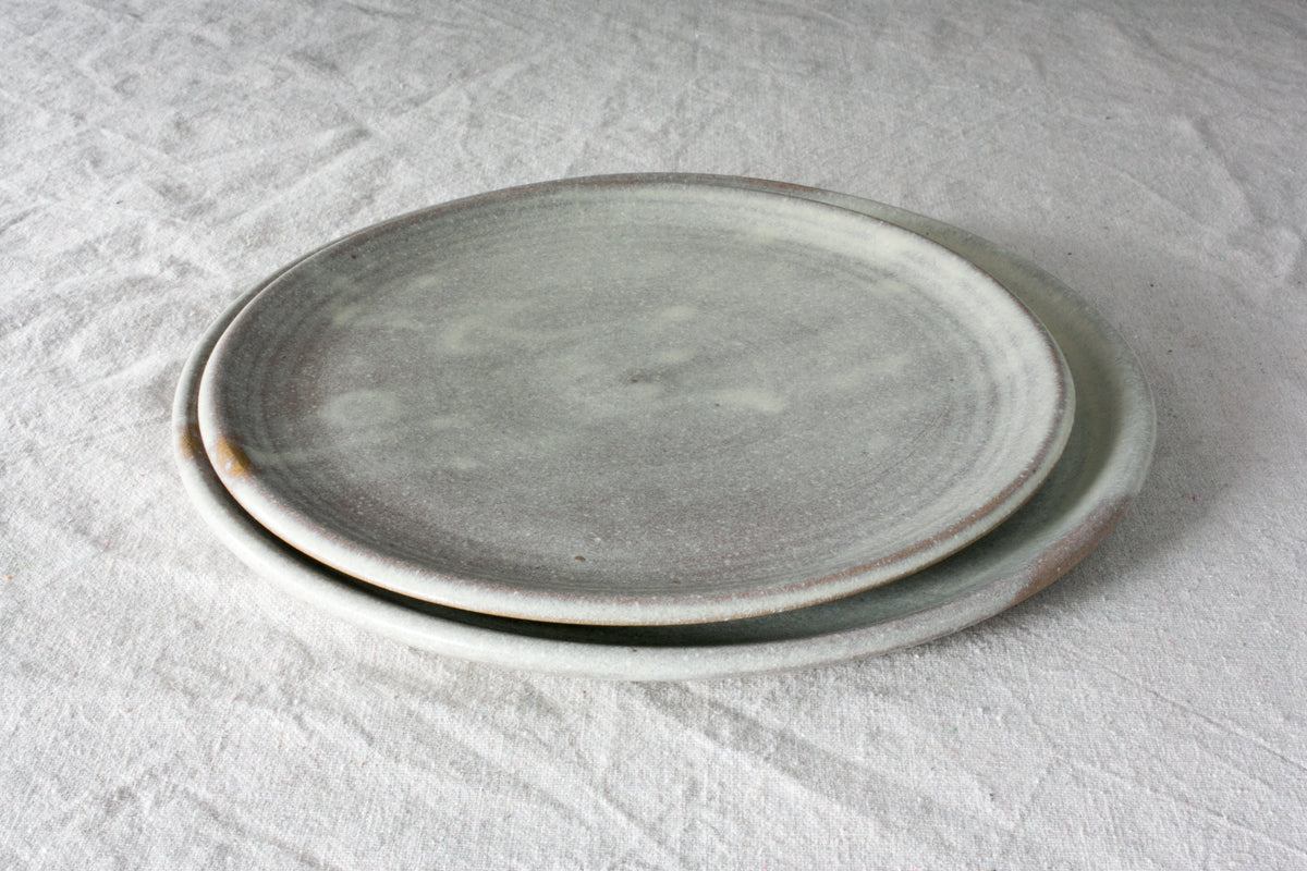 Horizon Dinner Plate: low angled stack of two round ceramic plates resting on textured linen fabric.