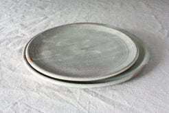 Horizon Lunch Plate stacked over a larger plate in a mottled matte gray glaze with a slight exposed raw rim, on linen.