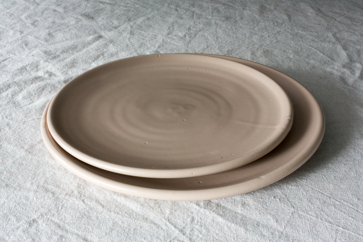 Horizon Dinner Plate: two stacked smooth stoneware plates showing throwing rings on white textured linen.