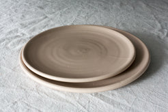 Horizon Dinner Plate: two stacked smooth stoneware plates showing throwing rings on white textured linen.