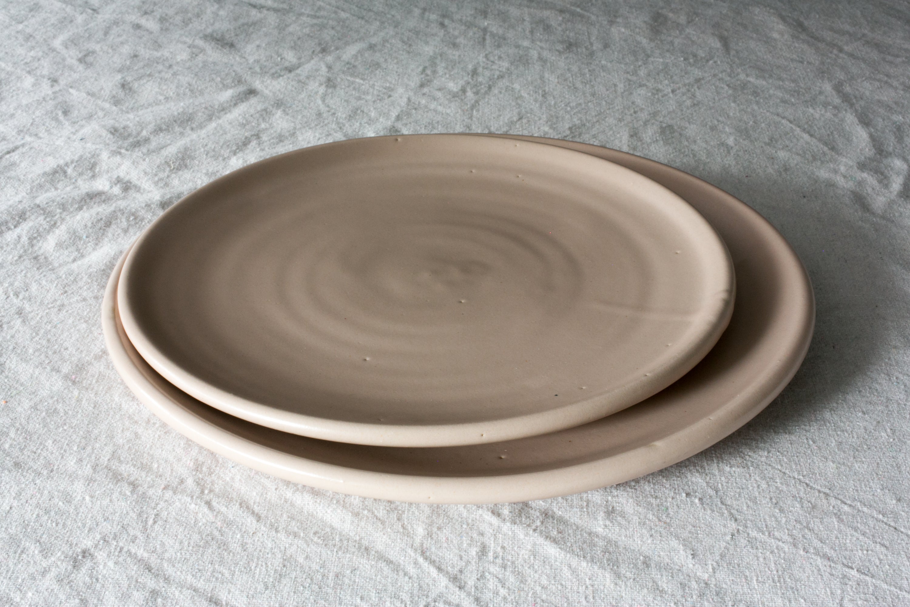 Horizon Dinner Plate: two stacked smooth stoneware plates showing throwing rings on white textured linen.