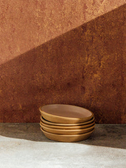Fat Rim Dinner Plate stack of five pieces with blush glaze, set against a warm terracotta backdrop.