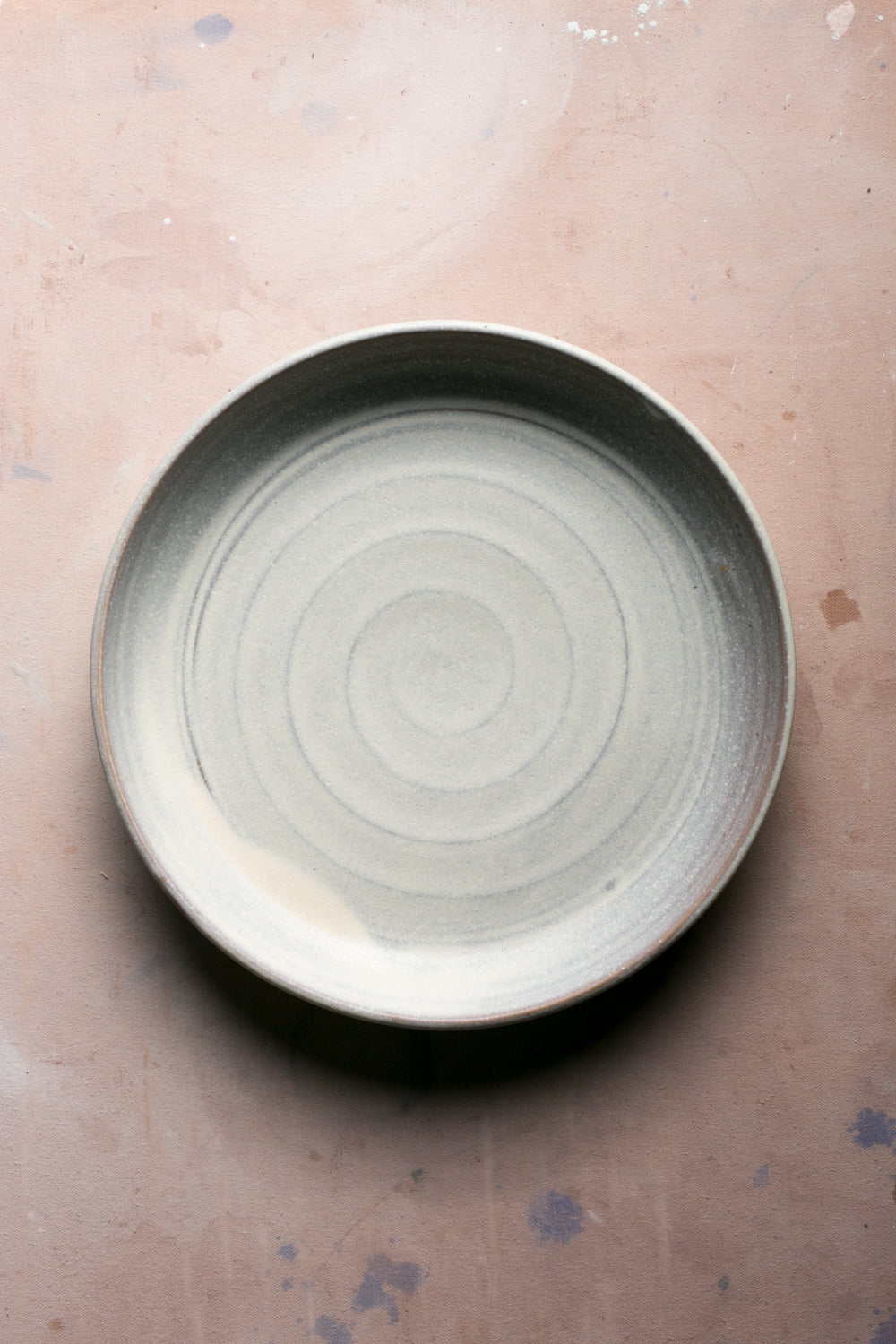 Wander Serving Platter in a pale glaze with spiral throwing rings, shown from above on a studio surface.