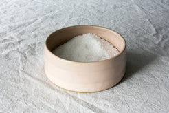 Wander Salt Pig: pale pink open-top ceramic salt cellar heaped with white sea salt on textured linen.